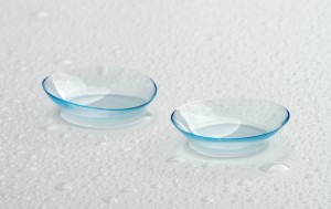 Two Contact Lenses with Water Droplets isolated on Grey Wet background